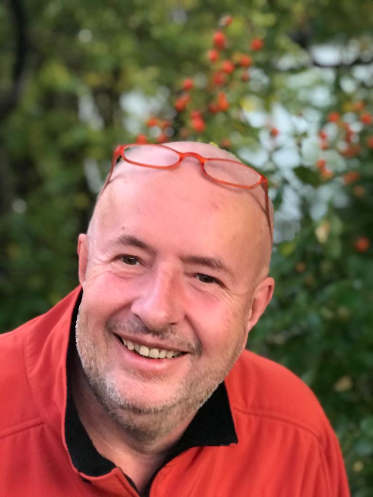 Rudolf Adlmanninger smiling outdoors in a red shirt